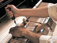 Imagen de un técnico trabajando en un piano. Vista de los martillos del interior